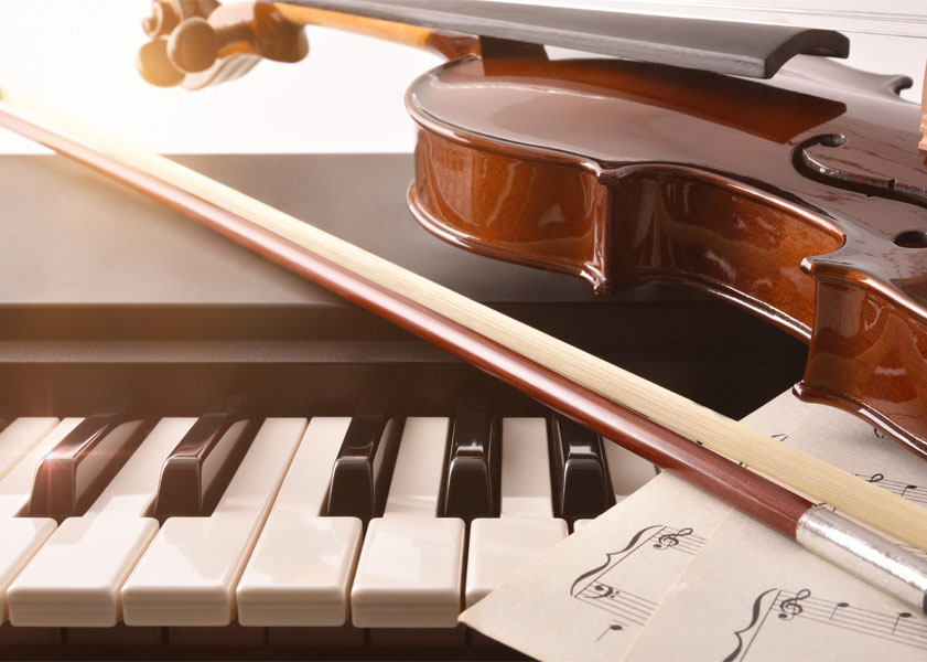 Violin and bow resting on a piano keyboard with sheet music.